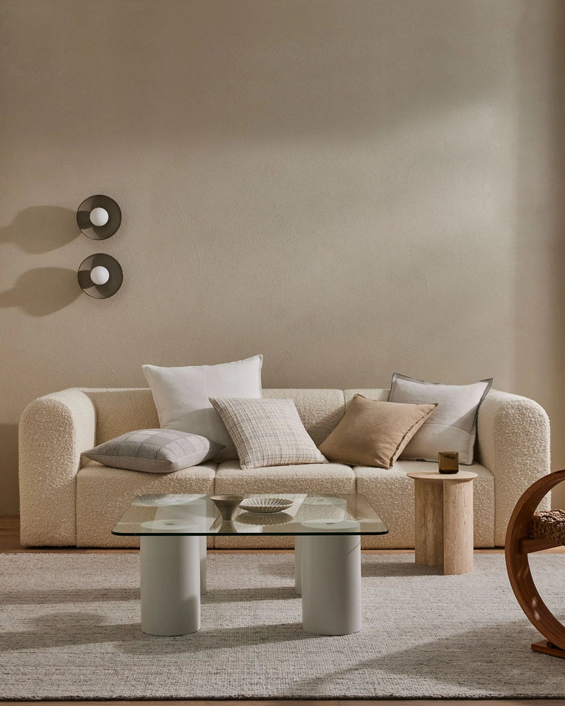 A sophisticated living room featuring an oatmeal-coloured rug and five different coloured cushions by Weave Home