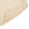 Close up of the corner of a textural wool blend boucle style rug by Globe West and Soren Liv NZ in shades of warm ivory and cream. The edge of the rug is flipped up, showing the underside. 