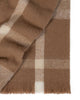 A folded wool blend throw blanket in shades of cream and brown in a stunning check pattern with fringed edges. 