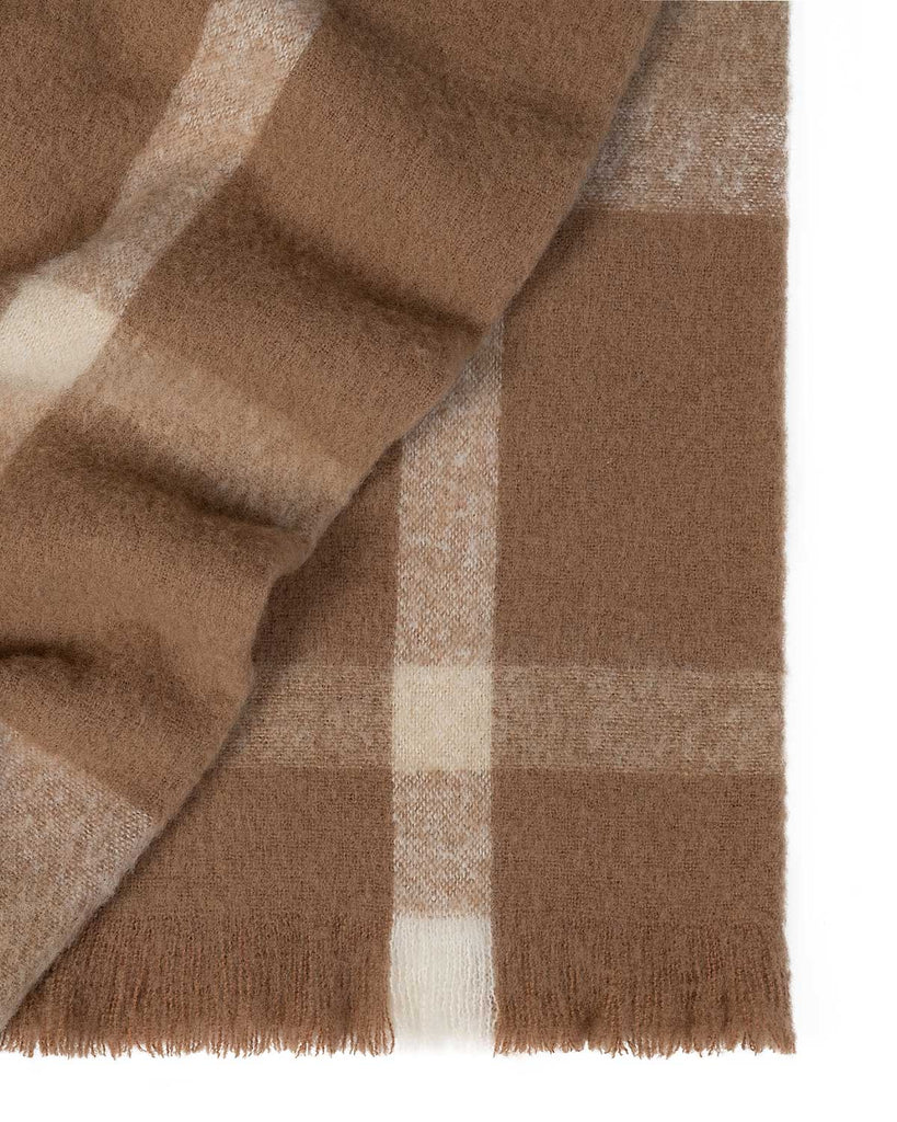 A folded wool blend throw blanket in shades of cream and brown in a stunning check pattern with fringed edges. 